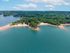 Breathtaking aerial view of a serene lakefront with lush green forests and sandy beaches, perfect for a tranquil getaway.