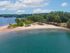 Scenic aerial view of a tranquil lakeside beach surrounded by lush greenery, perfect for relaxation and outdoor recreation.