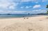 Serene sandy beach with vibrant blue waters and a breathtaking sky, perfect for relaxation and recreation.