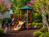 Charming outdoor playground with children enjoying the slide and climbing structure amid lush greenery and vibrant flowers, offering a perfect family-friendly environment.
