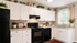 Charming modern kitchen with sleek black appliances, elegant white cabinetry, and granite countertops, illuminated by natural light through a large window.