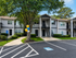 Charming apartment complex with two-story gray buildings, surrounded by lush greenery and accessible parking spaces, under a clear blue sky.