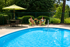 Inviting outdoor pool area with lush greenery and seating, perfect for relaxation and socializing under a stylish umbrella.