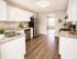 Bright and modern kitchen featuring sleek stainless steel appliances, elegant granite countertops, and chic white cabinetry, offering a welcoming and stylish cooking space.