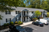 Charming apartment building with stylish gray siding, set amidst lush green landscaping and ample parking.