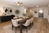Elegant dining area in modern apartment, featuring a wooden table, comfortable chairs, artistic decor, and contemporary lighting. Spacious layout with natural wood flooring and a bright kitchen visible in the background.