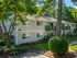 Charming two-story apartment building surrounded by lush greenery, featuring balconies with scenic views.