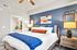 Chic bedroom featuring modern decor with a plush bed, stylish blue accent wall, and warm lighting for a cozy ambiance.