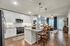 Elegant modern kitchen with sleek white cabinetry, stainless steel appliances, and a cozy breakfast bar overlooking a stylish open-plan living area.
