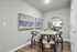 Chic dining area with elegant round table, modern navy chairs, and ocean-inspired artwork, creating a serene, inviting ambiance.