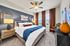 Elegant bedroom featuring a plush bed with blue accents, stylish decor, and large windows allowing natural light to flood the space.