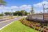 Inviting entrance of The Grove with vibrant flower beds and a welcoming stone sign under a clear blue sky.