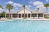 Inviting poolside view with pristine blue water and stylish loungers, set against a beautiful clubhouse backdrop and palm trees.