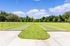 Spacious outdoor area featuring two bocce ball courts surrounded by lush greenery under a clear blue sky.