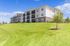 Charming modern apartment complex with spacious balconies and lush green surroundings under a clear blue sky.