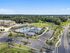 Aerial view of a luxurious apartment complex with spacious pool, lush greenery, and modern tennis courts, offering premium outdoor amenities.