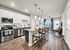 Modern open-concept kitchen and living area with sleek stainless steel appliances, elegant pendant lighting, and a cozy seating nook, perfect for entertaining.