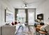 Sleek and modern living room with a cozy gray sofa, stylish decor, and sunlight streaming through large windows.