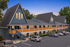 Charming chalet-style apartment building with modern wood accents, expansive windows, and ample parking under a clear evening sky.