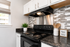 Modern kitchen corner with sleek black stove, stylish backsplash, and charming decor accents, ideal for a contemporary home.