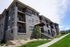 Elegant stone-accented apartment complex with spacious balconies and lush landscaping under a clear blue sky.
