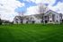 Charming residential building with elegant balconies and well-maintained green lawns under a vibrant sky.
