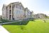 Charming apartment complex with stone facade, surrounded by lush green lawns and vibrant landscaping.