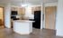 Bright open-concept kitchen with modern appliances, wood cabinetry, and a stylish island in a cozy apartment.