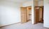 Bright and cozy bedroom with plush carpeting, open closet space, and elegant wooden doors.