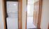Convenient in-unit laundry with a modern stacked washer and dryer beside a sunlit carpeted room.