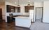 Modern apartment kitchen with sleek dark wood cabinets, stainless steel appliances, and a spacious island.