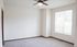 Bright and inviting empty room featuring plush carpeting, large window, and modern ceiling fan, perfect for a personalized space.