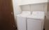 Bright laundry room featuring modern washer and dryer, with convenient overhead shelving for storage.