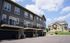 Modern townhouse complex with spacious balconies and attached garages in a serene suburban neighborhood.