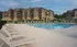 Elegant apartment complex with a pristine pool area surrounded by comfortable lounge chairs, perfect for relaxation.