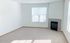 Bright and cozy living room with large window and elegant fireplace, featuring plush carpeting and abundant natural light.