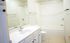 Bright and inviting bathroom with elegant fixtures, a large mirror, and a relaxing bathtub.