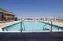 Inviting rooftop pool with clear blue water, surrounded by elegant lounge chairs under a bright sky.