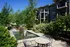 Charming apartment exterior with lush green landscaping, a serene water feature, and inviting outdoor seating, perfect for relaxation.