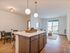 Bright open-plan living space featuring a modern kitchen island, cozy dining area, and inviting living room with large glass doors leading to a sunny patio.