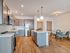 Modern open-plan kitchen and dining area with warm wood flooring, sleek cabinets, and contemporary lighting.