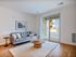 Bright, modern living room with a stylish gray sofa, elegant wooden coffee table, and large sliding glass doors leading to a sunny patio.