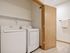 Modern laundry room with sleek washer and dryer, accented by wooden door and elegant towel rack.