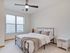 Bright and airy bedroom featuring a cozy bed with soft linens, large window with blinds, and a sleek ceiling fan.