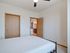 Bright bedroom with cozy bed and open doorway leading to a modern kitchen, featuring warm wooden accents.