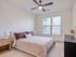 Bright and inviting bedroom featuring a cozy bed, modern ceiling fan, and large window for ample natural light.
