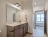 Elegant bathroom with modern fixtures, double vanity, and a doorway leading to a bright bedroom with large windows.