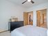 Elegant bedroom with a sleek black dresser, wall art, and open doors leading to a cozy dining area and spacious closet.