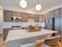 Modern kitchen with sleek cabinetry, stainless steel appliances, and a spacious island featuring woven barstools and stylish lighting.