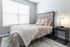 Elegant bedroom featuring a plush bed with a geometric headboard, soft textiles, and a modern bedside lamp.